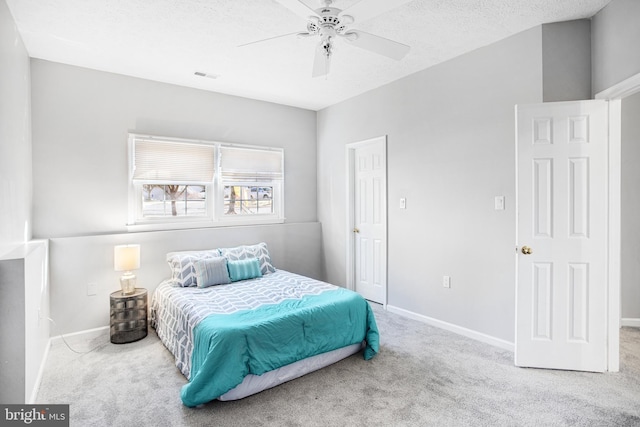 carpeted bedroom featuring ceiling fan and a textured ceiling