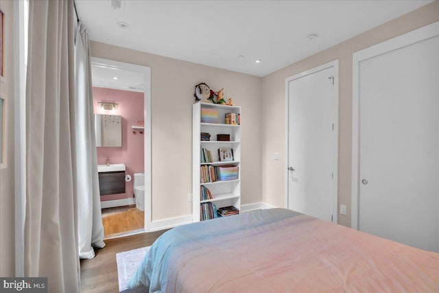 bedroom featuring ensuite bath and light hardwood / wood-style flooring