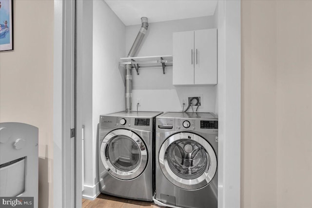 laundry area featuring cabinets, washer and dryer, and light hardwood / wood-style flooring