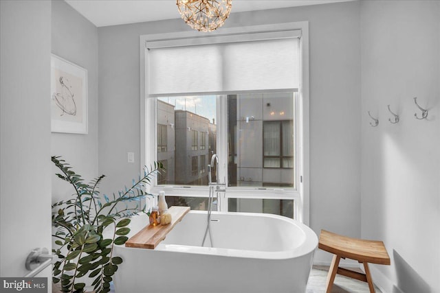 bathroom with a bathing tub, sink, and a notable chandelier