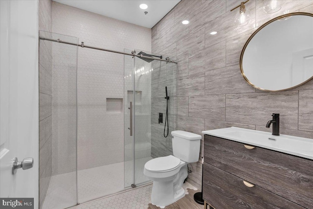 bathroom featuring tile patterned floors, toilet, tile walls, vanity, and a shower with door