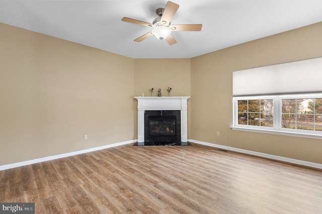 unfurnished living room featuring ceiling fan, a high end fireplace, and light hardwood / wood-style floors