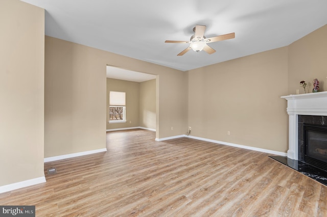 unfurnished living room featuring ceiling fan, light wood-type flooring, and a high end fireplace