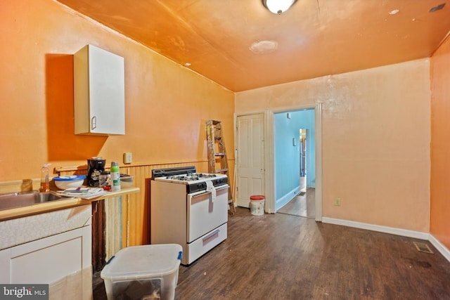 kitchen featuring sink, dark hardwood / wood-style floors, gas range gas stove, and white cabinets