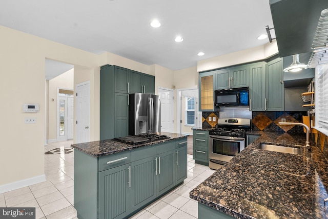 kitchen featuring dark stone countertops, sink, green cabinets, and appliances with stainless steel finishes