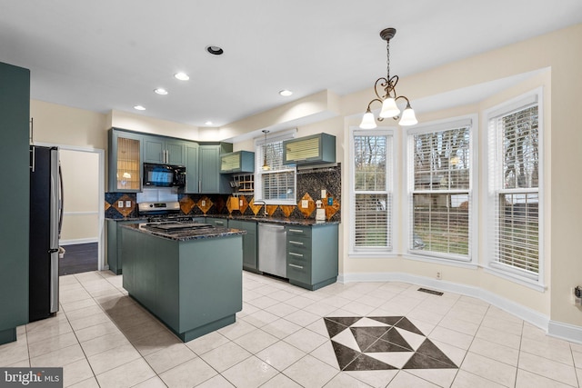 kitchen with stainless steel appliances, a kitchen island, light tile patterned floors, and decorative light fixtures