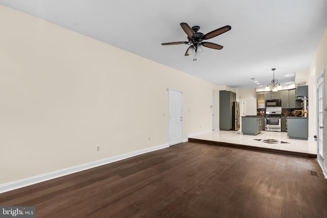 unfurnished living room featuring ceiling fan with notable chandelier and light wood-type flooring