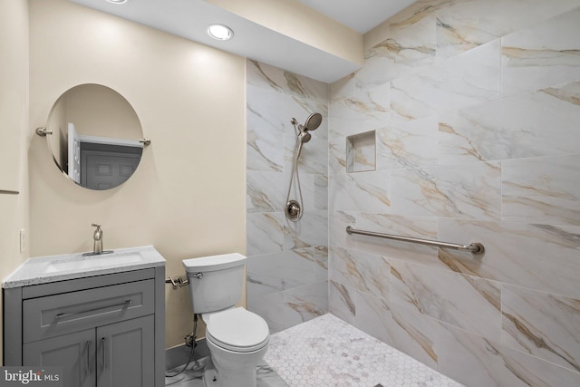 bathroom with tiled shower, vanity, and toilet