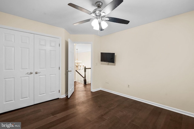 unfurnished bedroom featuring ceiling fan with notable chandelier, dark hardwood / wood-style flooring, and a closet