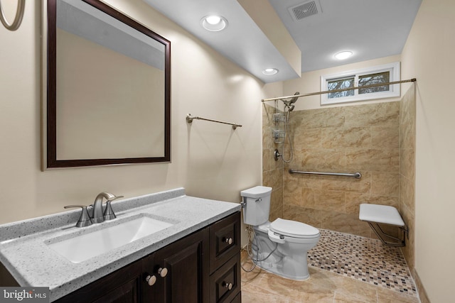 bathroom with vanity, tiled shower, and toilet