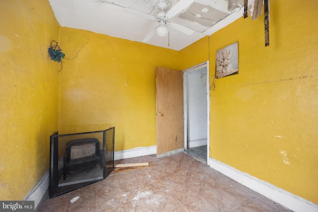 unfurnished living room with ceiling fan and a wood stove