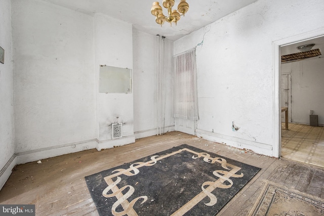 unfurnished room featuring hardwood / wood-style flooring and a notable chandelier