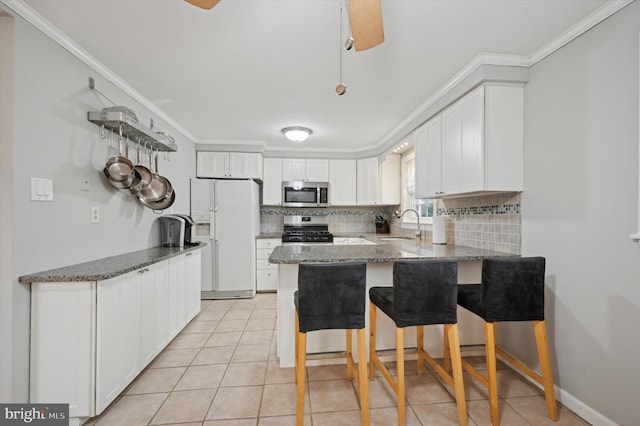 kitchen featuring a breakfast bar, white cabinets, backsplash, kitchen peninsula, and stainless steel appliances