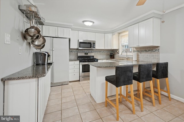 kitchen featuring a kitchen bar, sink, crown molding, appliances with stainless steel finishes, and white cabinets