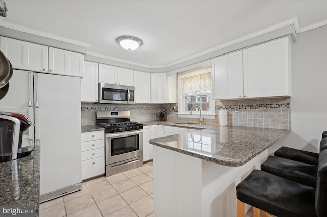 kitchen with sink, crown molding, white cabinetry, stainless steel appliances, and kitchen peninsula