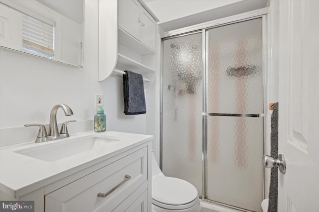 bathroom featuring vanity, a shower with shower door, and toilet