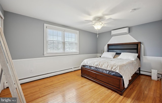 bedroom featuring a wall mounted air conditioner, hardwood / wood-style floors, ceiling fan, and a baseboard heating unit