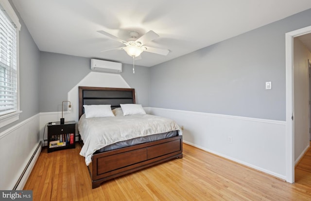 bedroom featuring baseboard heating, ceiling fan, wood-type flooring, and an AC wall unit