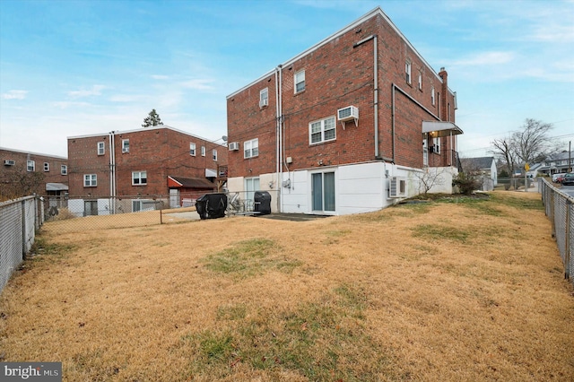 rear view of property with a wall mounted air conditioner and a lawn