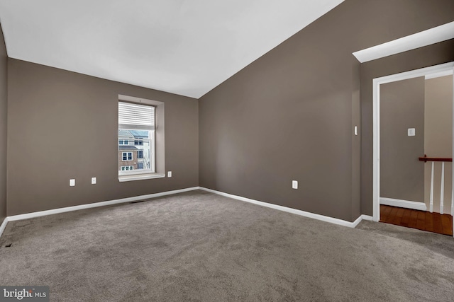 carpeted spare room with vaulted ceiling