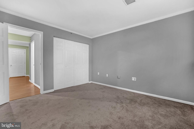 unfurnished bedroom with crown molding, carpet flooring, and a closet