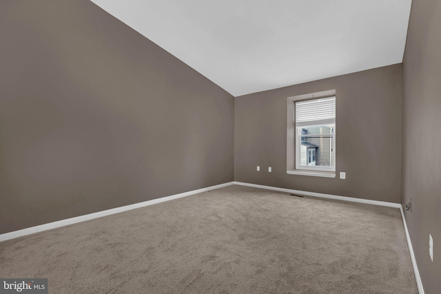 empty room featuring vaulted ceiling and carpet