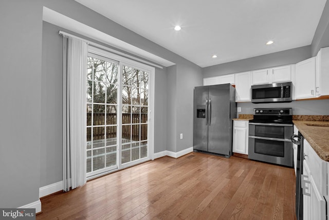 kitchen with white cabinetry, appliances with stainless steel finishes, stone countertops, and light hardwood / wood-style flooring