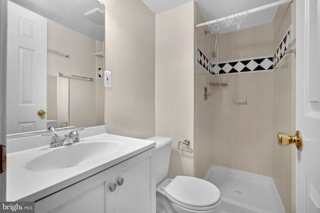 bathroom featuring vanity, a tile shower, and toilet