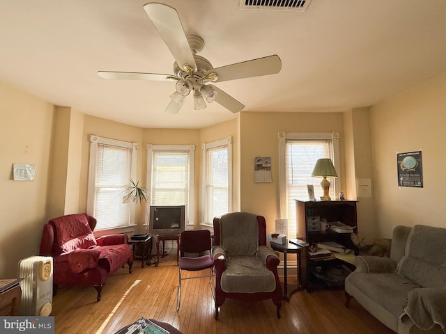 living area with hardwood / wood-style floors and ceiling fan