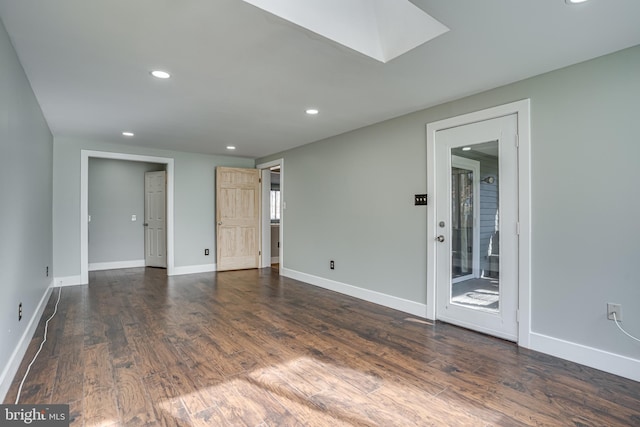 spare room with dark hardwood / wood-style flooring and a skylight