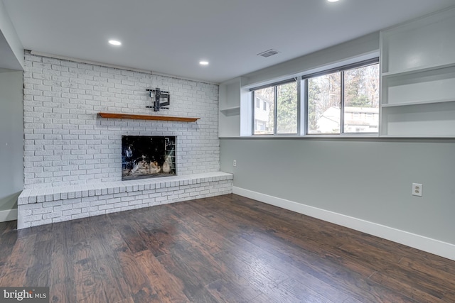 unfurnished living room with dark hardwood / wood-style flooring and a brick fireplace