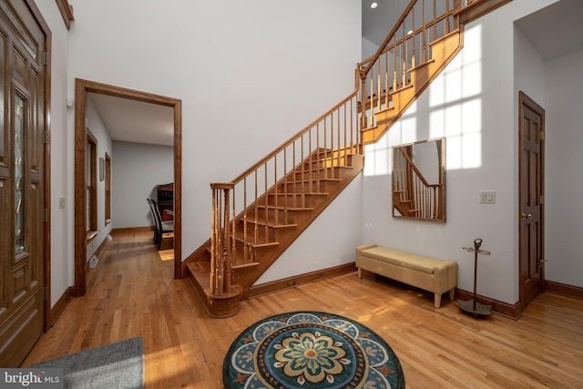 stairway with a towering ceiling and wood-type flooring