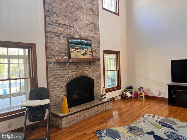 living room with hardwood / wood-style flooring, a fireplace, and a high ceiling