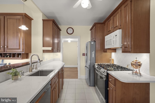 kitchen with sink, light tile patterned floors, appliances with stainless steel finishes, hanging light fixtures, and tasteful backsplash