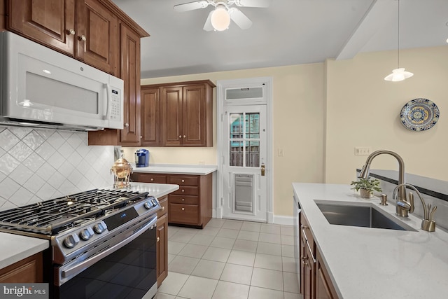 kitchen with decorative light fixtures, sink, decorative backsplash, light tile patterned floors, and stainless steel gas range