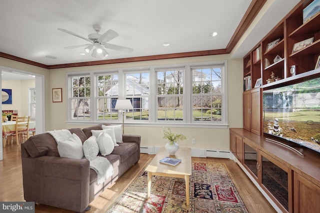 living room featuring ornamental molding, light wood-type flooring, ceiling fan, and baseboard heating