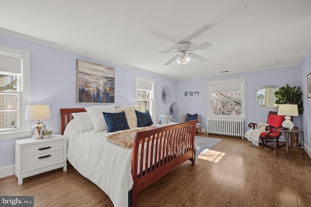 bedroom featuring ceiling fan, ornamental molding, dark hardwood / wood-style floors, and radiator