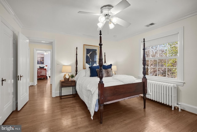 bedroom with ceiling fan, radiator, and dark hardwood / wood-style flooring