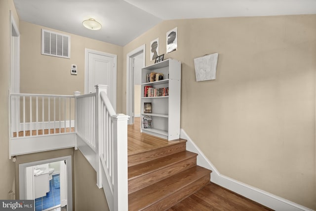 stairway featuring wood-type flooring and vaulted ceiling