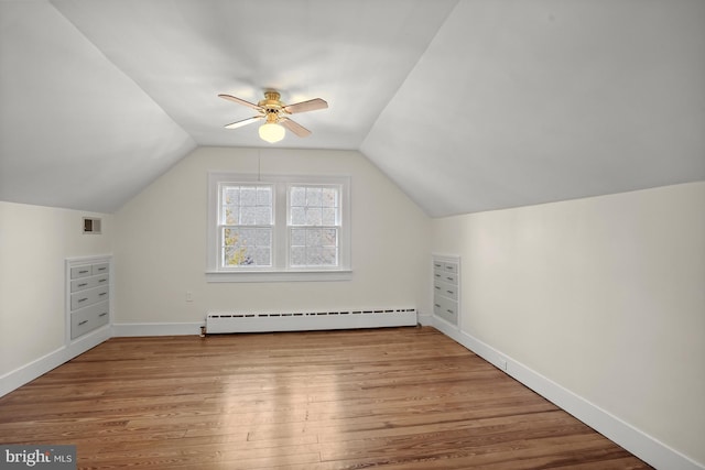 additional living space with light hardwood / wood-style flooring, a baseboard radiator, ceiling fan, and vaulted ceiling