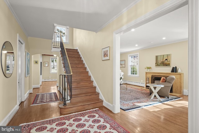 staircase with crown molding, hardwood / wood-style flooring, and baseboard heating