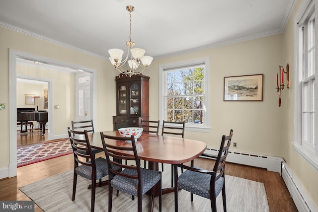 dining space featuring ornamental molding, dark wood-type flooring, a notable chandelier, and baseboard heating