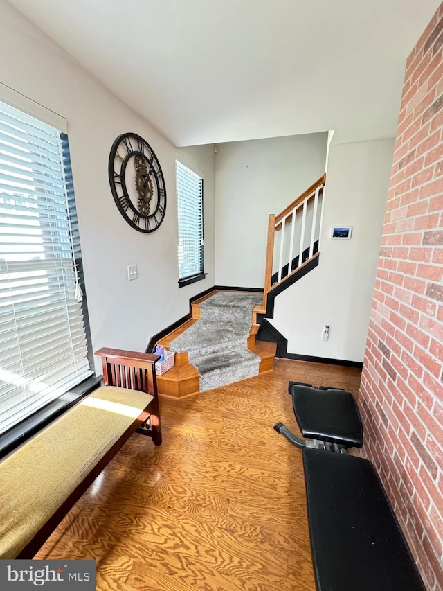 foyer entrance with hardwood / wood-style floors, plenty of natural light, and brick wall