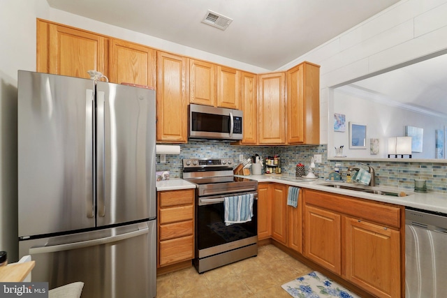 kitchen with ornamental molding, appliances with stainless steel finishes, sink, and backsplash