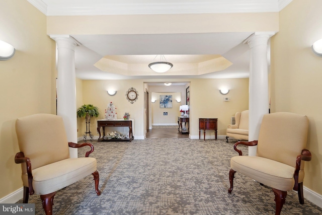 sitting room with dark carpet, ornamental molding, a tray ceiling, and decorative columns