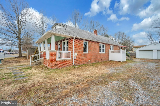 view of side of home with a garage, an outdoor structure, and a porch