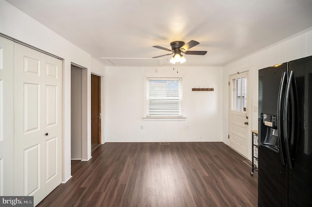 interior space featuring multiple windows, black fridge with ice dispenser, dark hardwood / wood-style floors, and ceiling fan