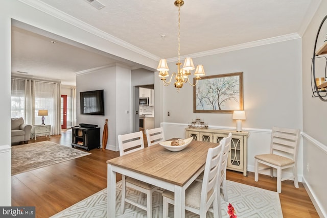 dining area featuring crown molding, light hardwood / wood-style flooring, and a chandelier