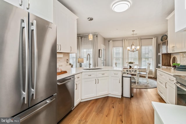 kitchen with stainless steel appliances, sink, hanging light fixtures, and white cabinets