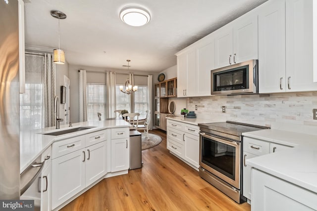 kitchen featuring pendant lighting, sink, stainless steel appliances, white cabinets, and light wood-type flooring